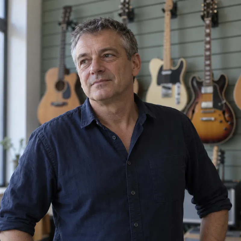 Laurent Vercelot devant un mur de guitares